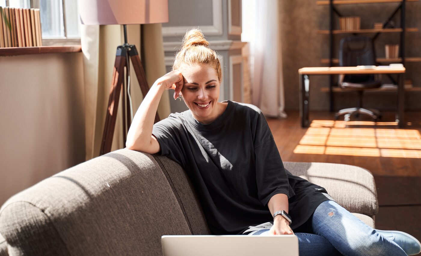A woman sitting on her sofa with a laptop, reflecting quietly at home