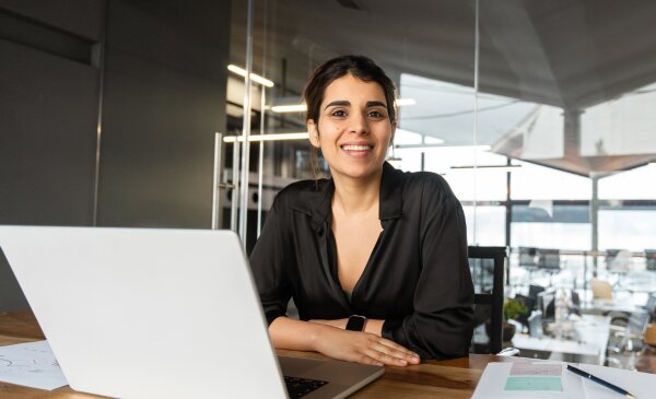 A woman smiling warmly during an online session, feeling supported